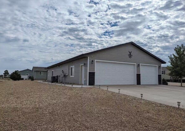 Ein einstöckiges Gebäude mit Garage, Auffahrt und Kiesfläche davor.