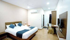 A hotel room with a wooden bed, a small desk, a chair, a TV, and an air conditioning unit. - Melody mings (Hyderabad)