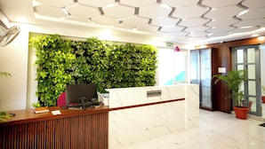 A reception desk with a green wall, a marble counter, and a ceiling with hexagonal patterns. - Melody mings (Hyderabad)