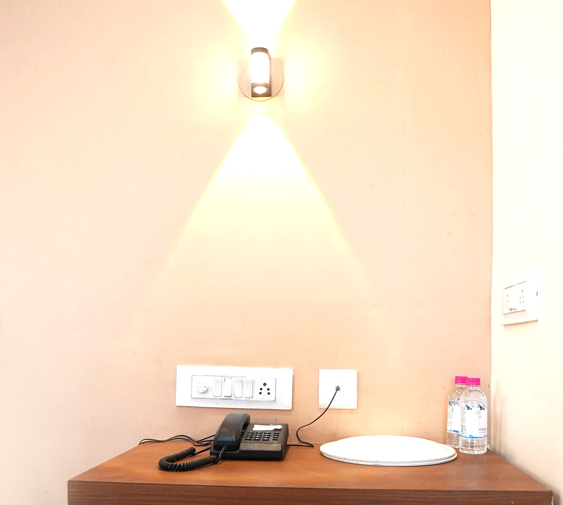 A wooden desk with a telephone, a plate, and a water bottle.