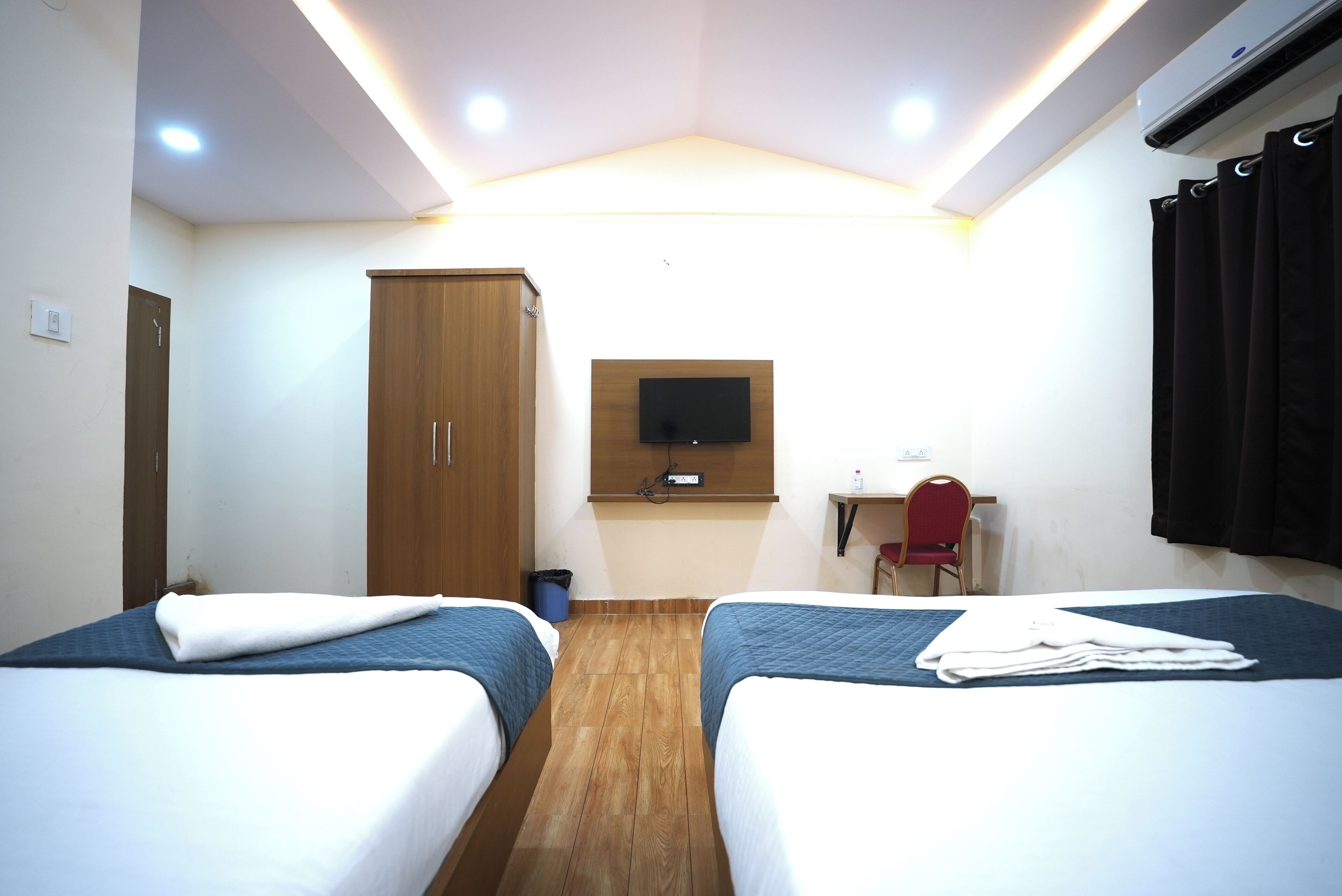 Habitación de hotel con dos camas, un escritorio, un televisor y un armario.