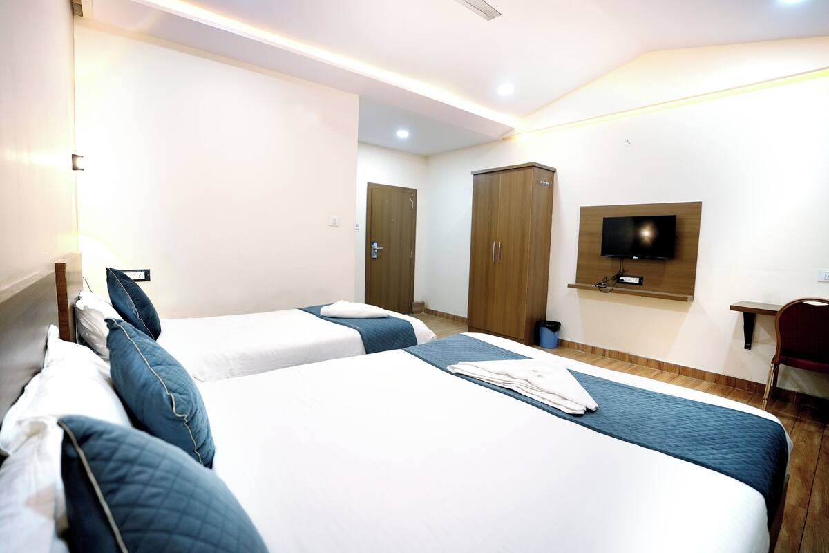 A hotel room with two beds, a TV mounted on the wall, and a wardrobe.