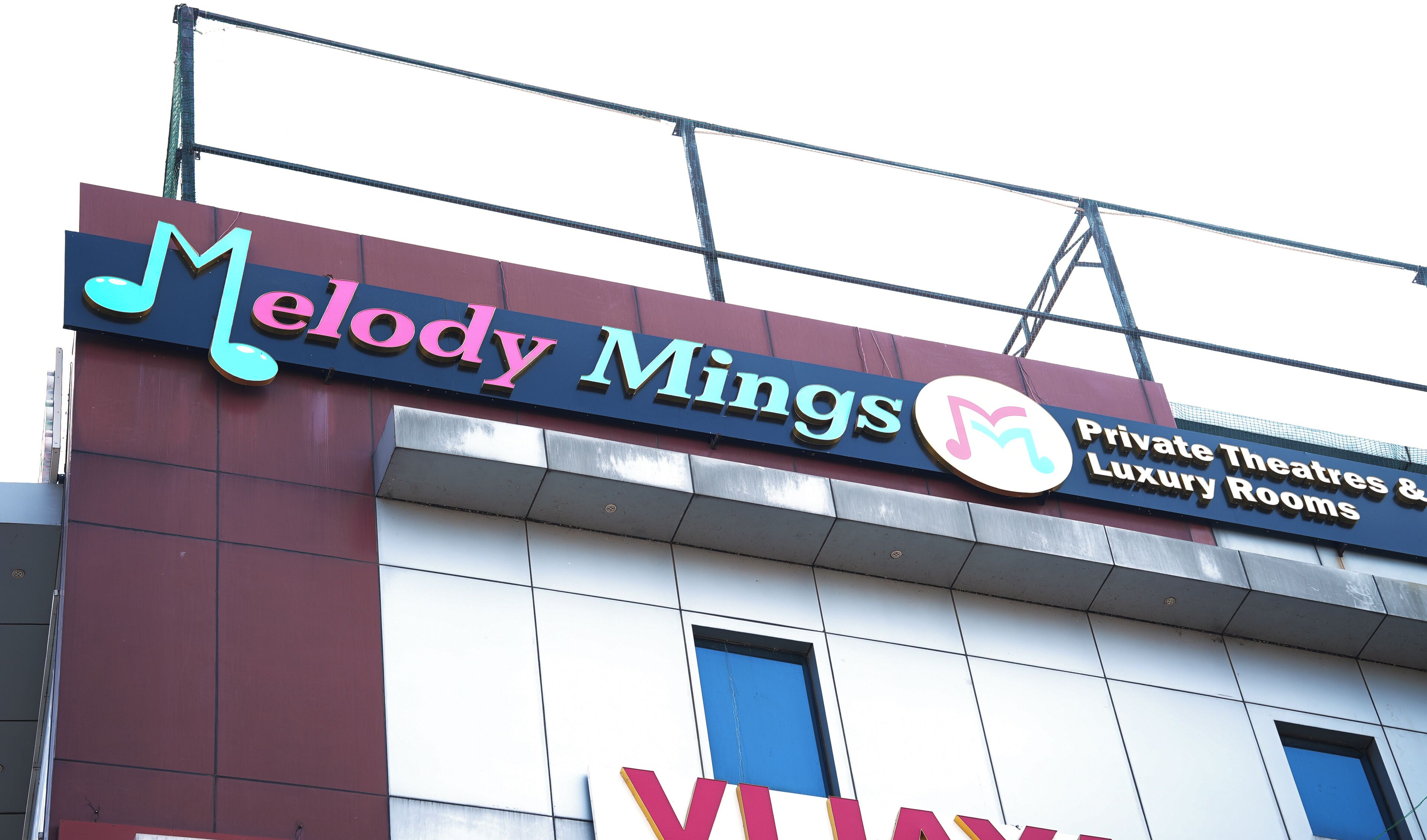 Un edificio con un cartello per 'Melody Mings', con un logo e testo che indica la presenza di teatri privati e camere di lusso.