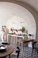 Una cocina acogedora con techo abovedado, estantes de madera y lámparas colgantes.