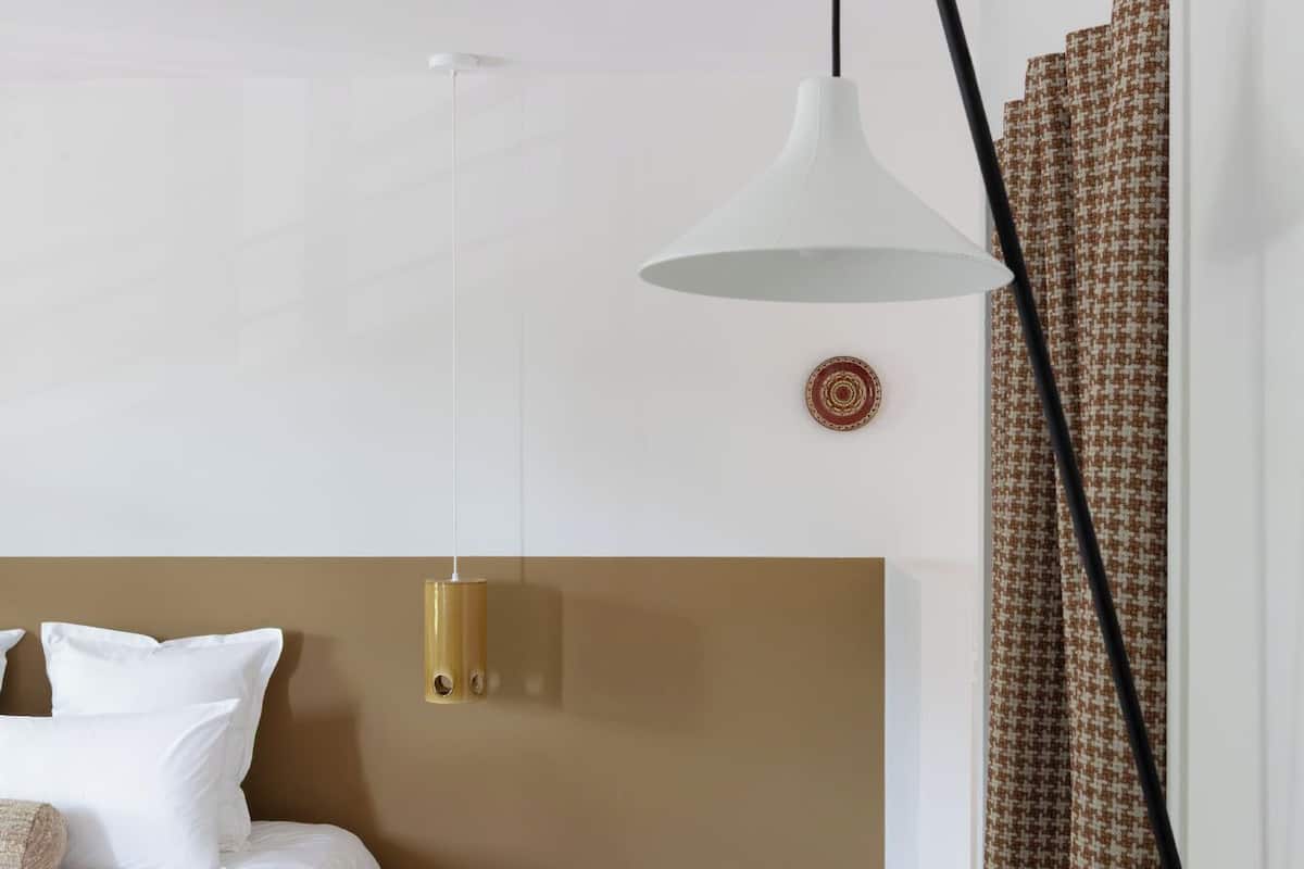 A bedroom with a bed, a bedside table, a lamp, and a patterned curtain.