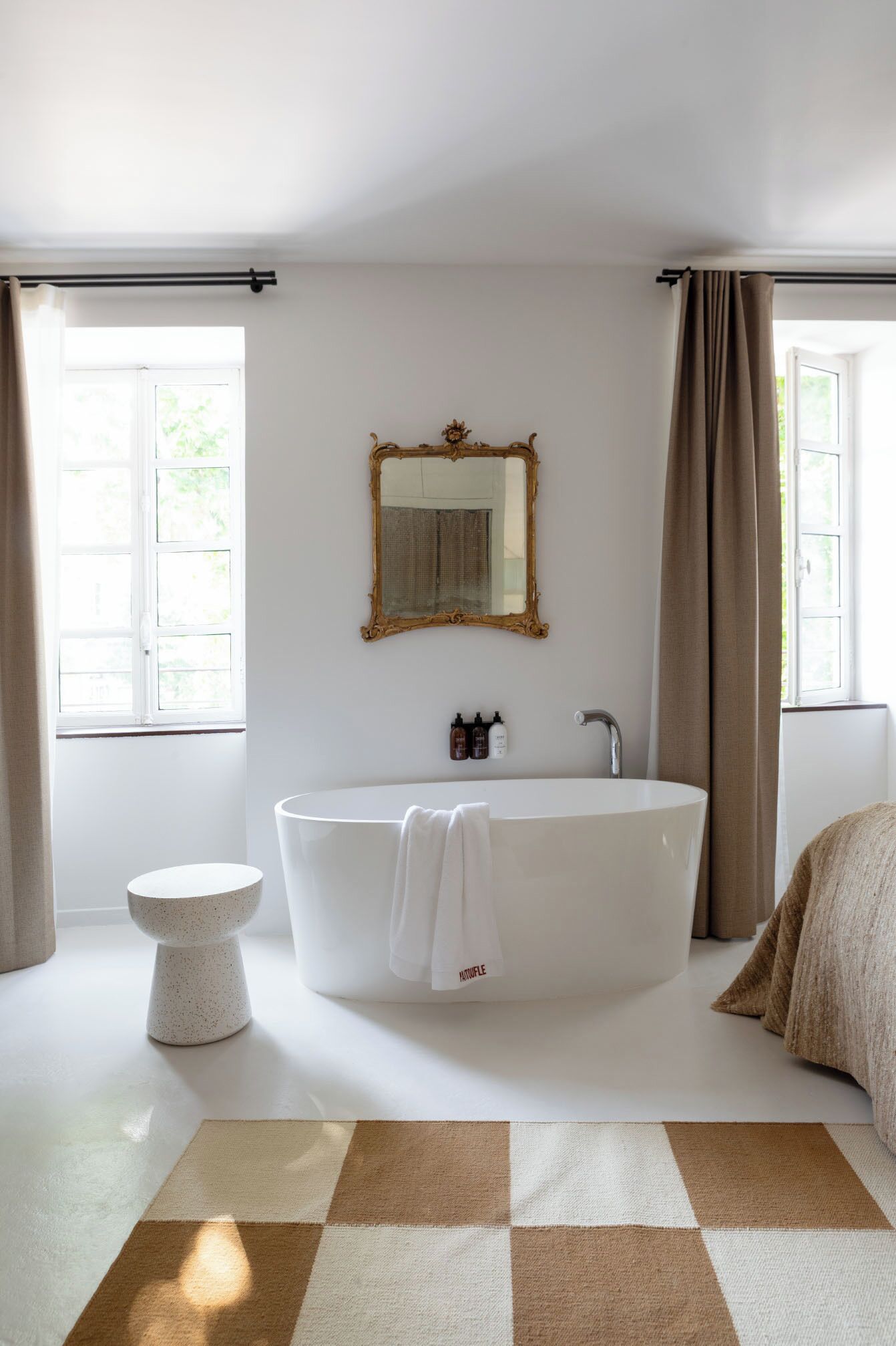 A modern bathroom with a freestanding bathtub, a round sink, and a large mirror.