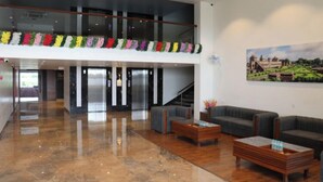 A spacious lobby with a polished marble floor, a staircase, and a seating area with sofas and a coffee table. - VS Imperial (Akola)
