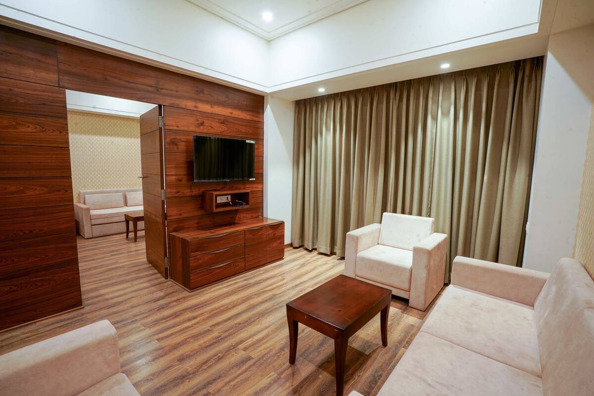 Una sala de estar moderna con piso de madera, televisor de pantalla plana, mueble de madera, una mesita de centro y dos sofás blancos.
