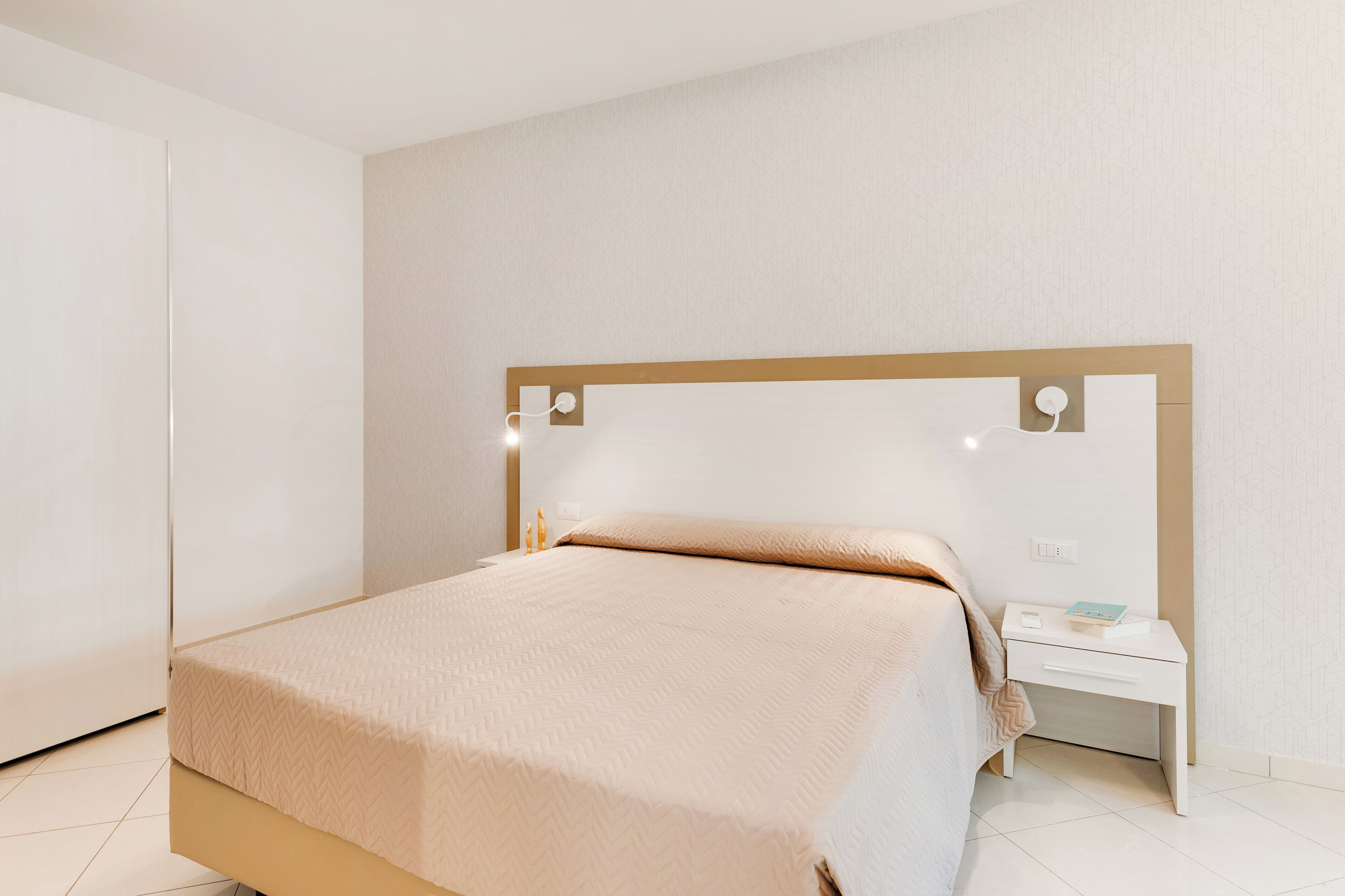 A neatly arranged bedroom with a bed, bedside table, and a nightstand.