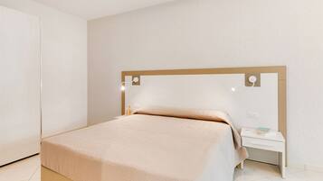 A neatly arranged bedroom with a bed, bedside table, and a nightstand.
