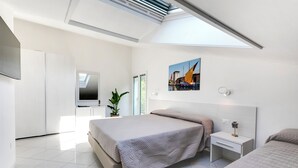 A modern bedroom with a skylight, a bed, a bedside table, and a wall-mounted TV. - Residenza Acquamarina - Siroli Collection (Cervia)