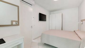 A bedroom with a bed, a wardrobe, a mirror, and an air conditioning unit.