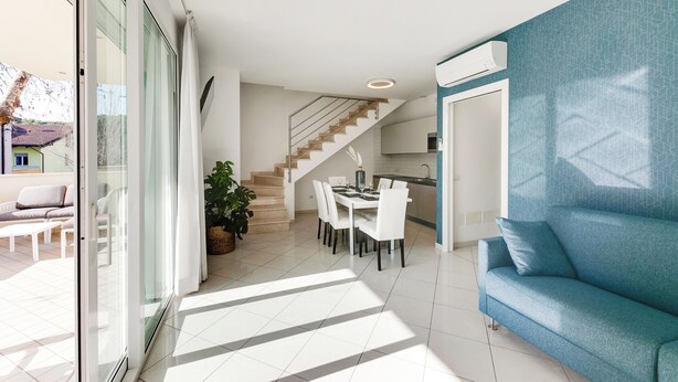 A modern living space with a dining area, a staircase, and a blue sofa. - Residenza Acquamarina - Siroli Collection (Cervia)
