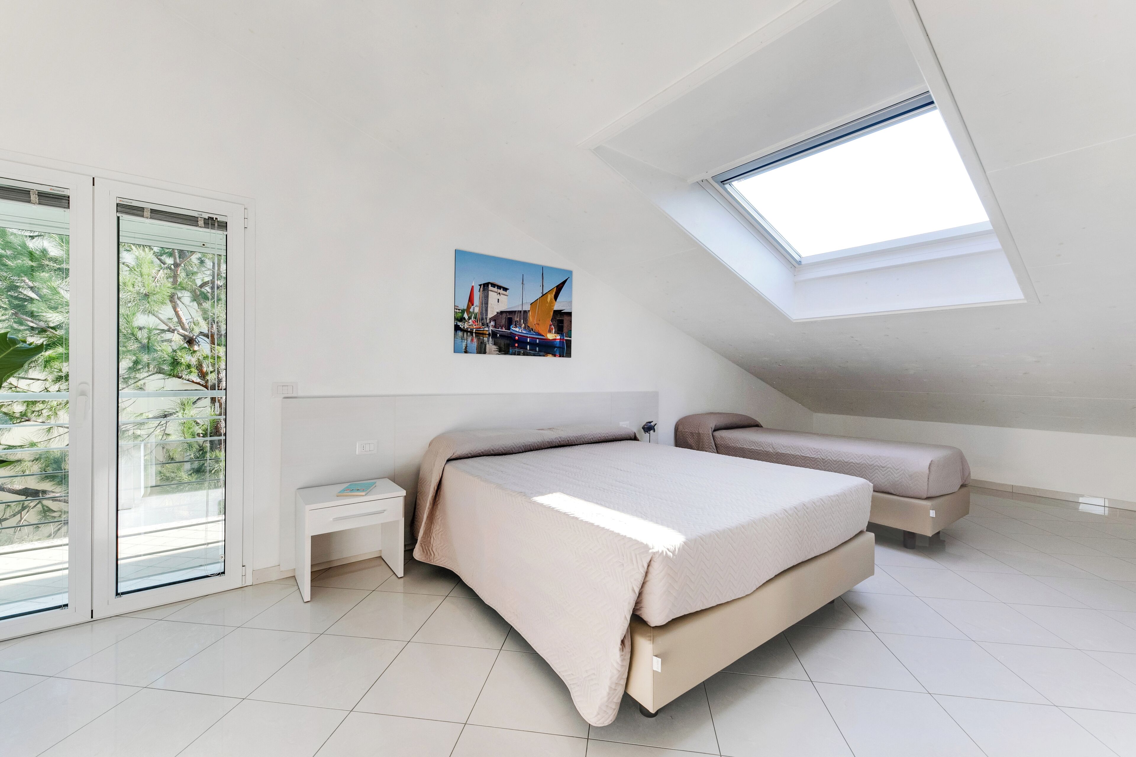 Une chambre à coucher avec un grand lit, une table de chevet, un banc et une lucarne.
