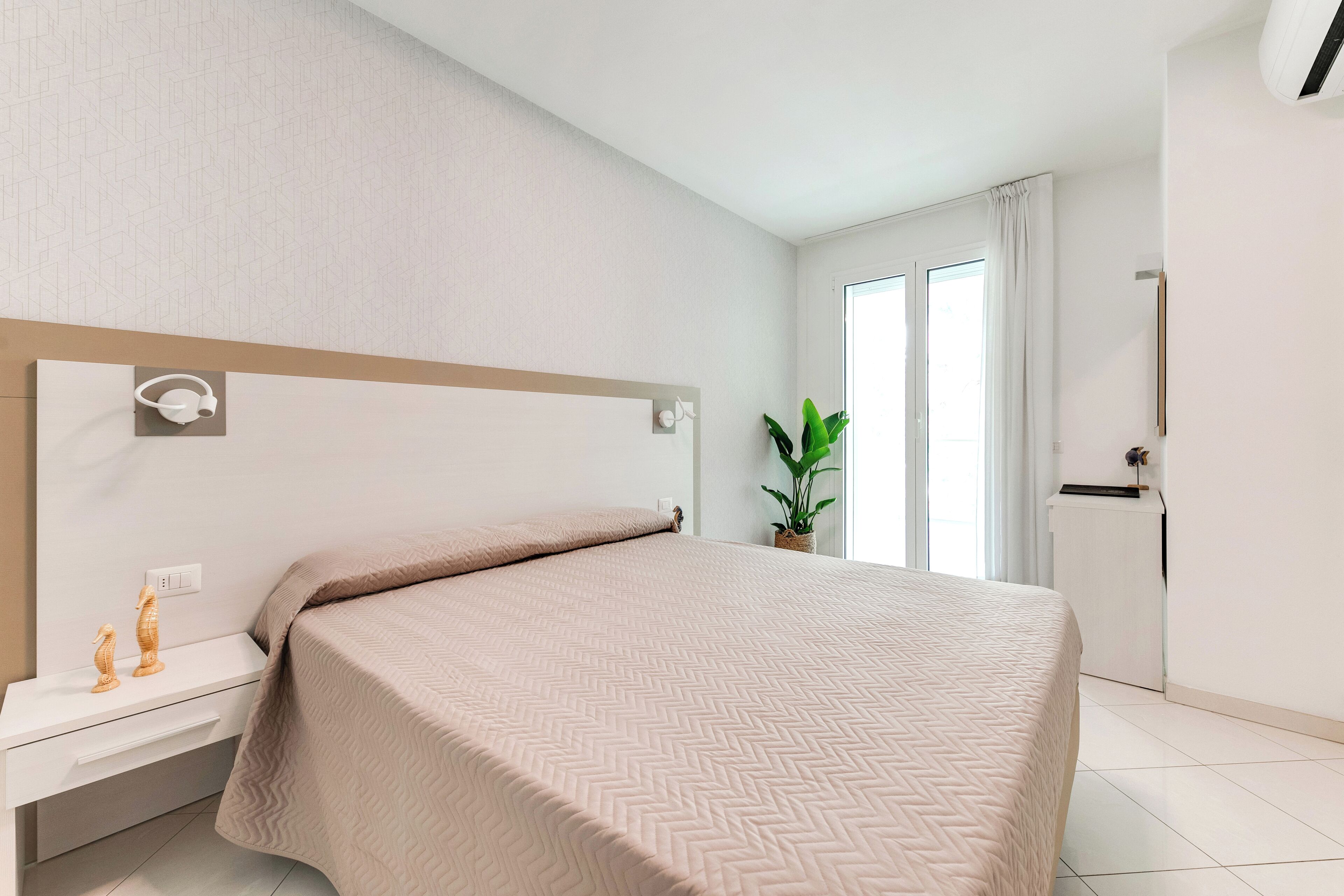 Une chambre à coucher moderne avec un lit, une table de chevet et une plante en pot.