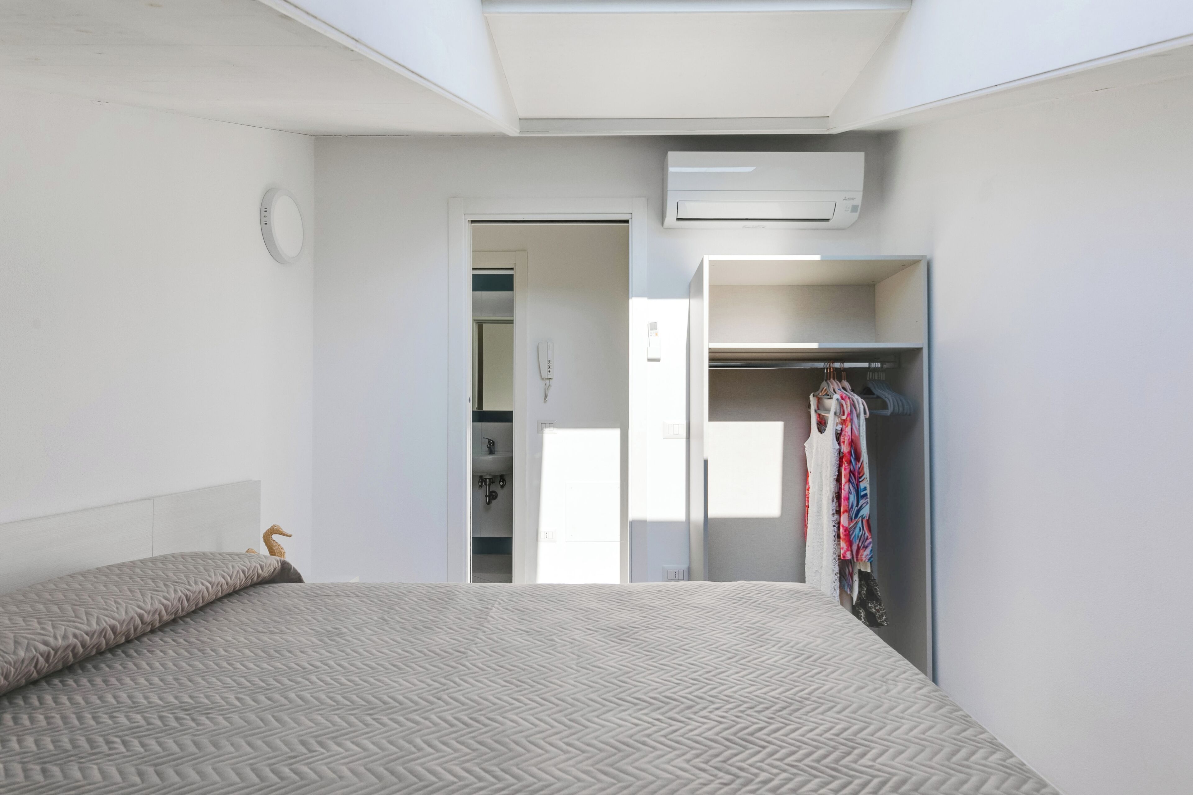 Ein Schlafzimmer mit Bett, Kleiderschrank und Klimaanlage.