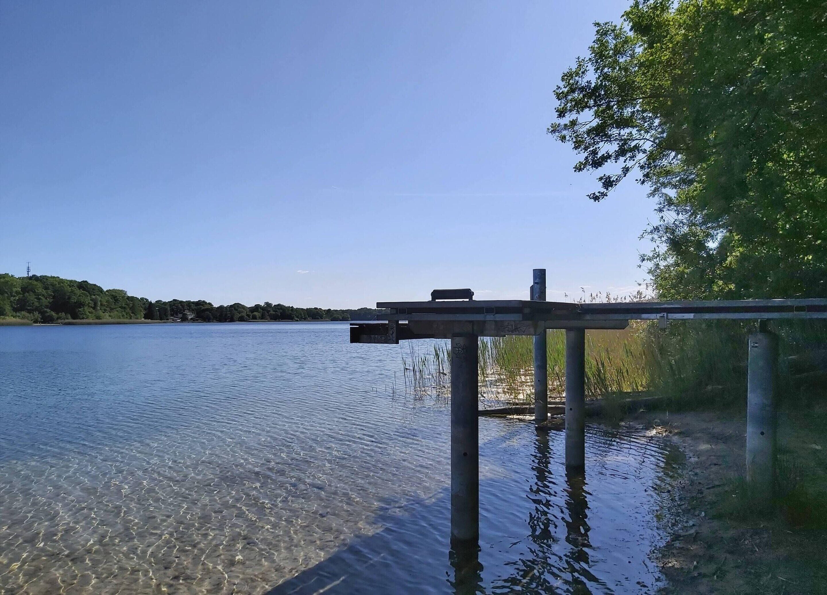 A clear lake with a dock extending into the water.
