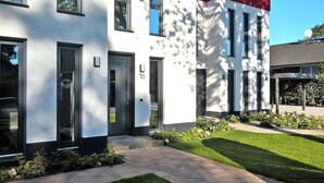 A modern building with a white facade, numbered doors, and a well-maintained lawn. - Appartement fur 4 Personen in Strausberg (Strausberg)