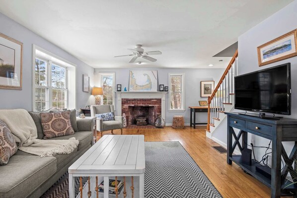 A living room with a fireplace, a television, and a staircase leading to another level.