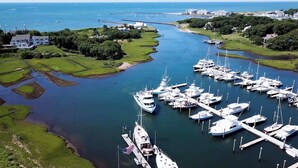 Un port de plaisance où sont amarrés de nombreux yachts, entouré d’une végétation luxuriante et dominé par un grand bâtiment blanc.