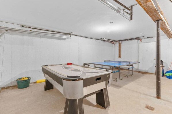 A room with a foosball table, ping pong table, and a pool table.