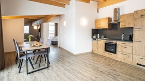 A modern kitchen with wooden cabinets and a dining area with a table and chairs. - Apartment 50 m From Obingleitn ski Lift (Fieberbrunn)