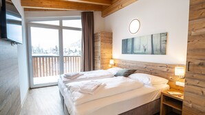 Un dormitorio con una cama grande, cabecera de madera y vistas a un balcón nevado.