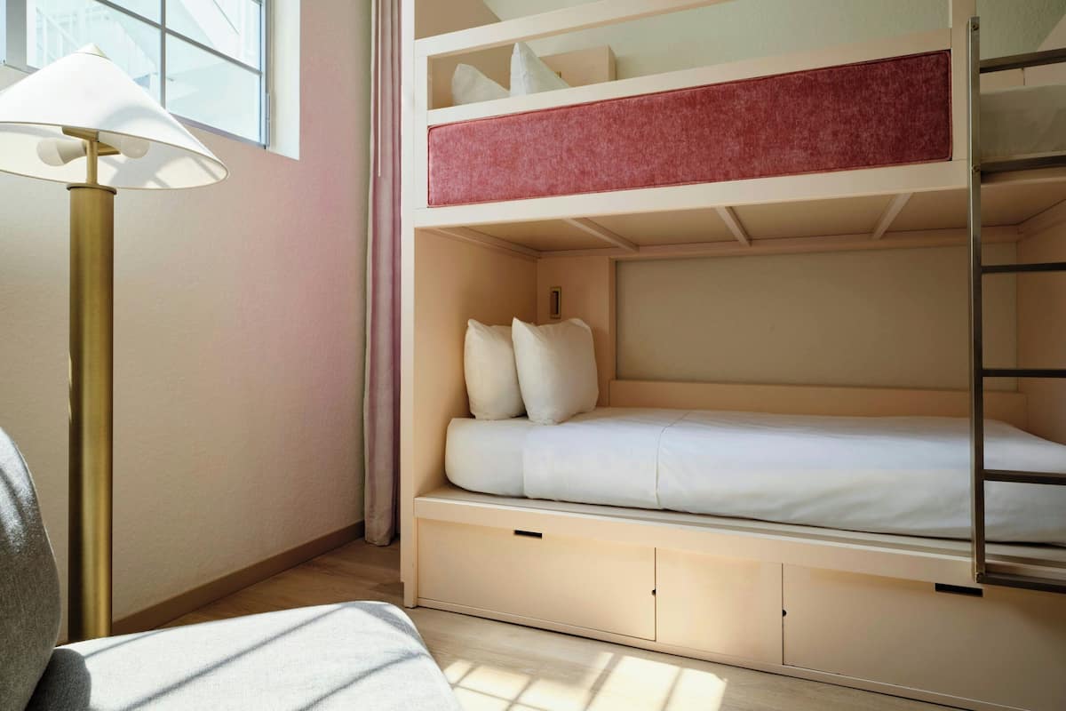 Un letto a castello con una scala, un comodino e una lampada.