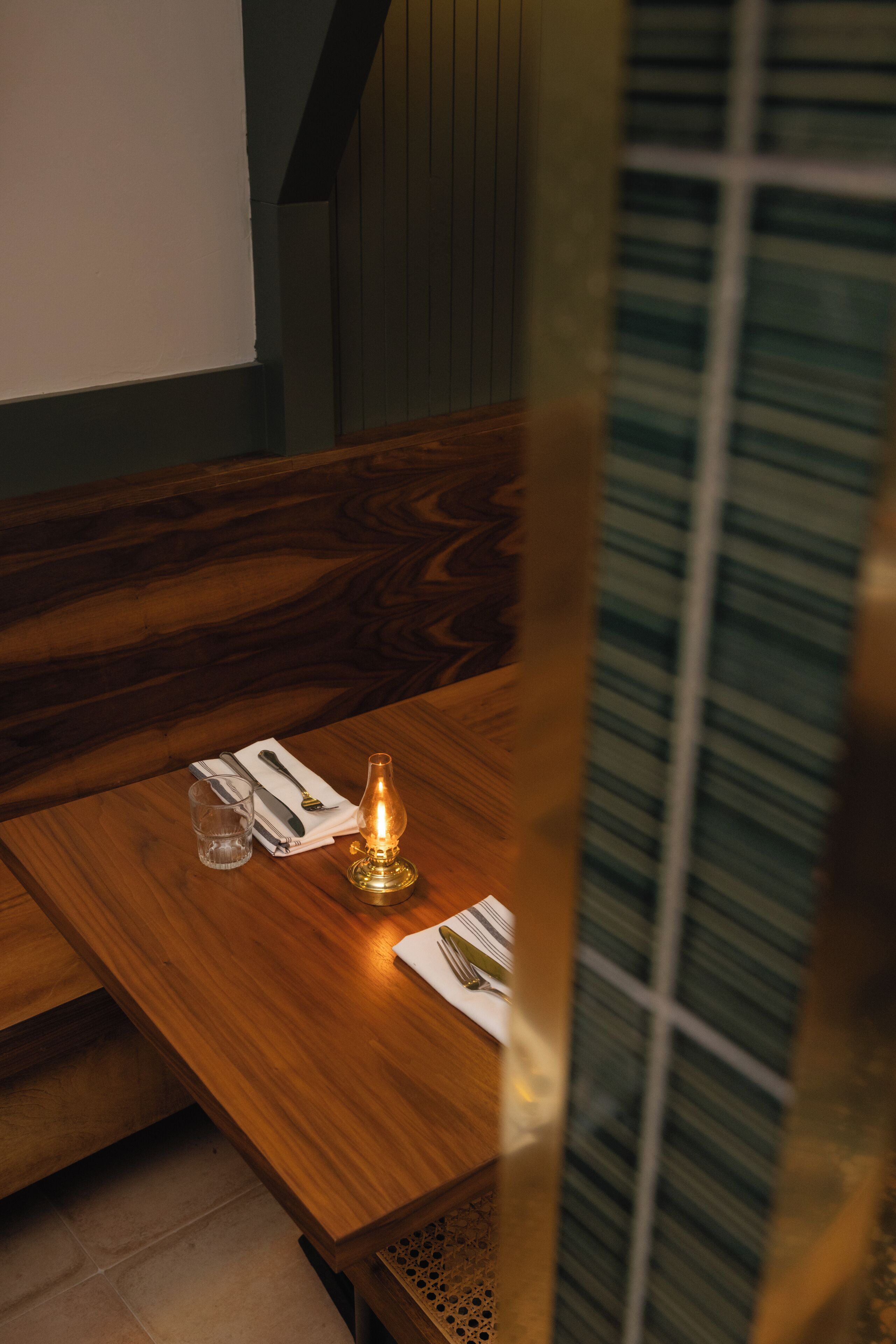 A wooden table with a candle, a glass, and a napkin.