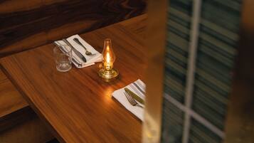 A wooden table with a candle, a glass, and a napkin.