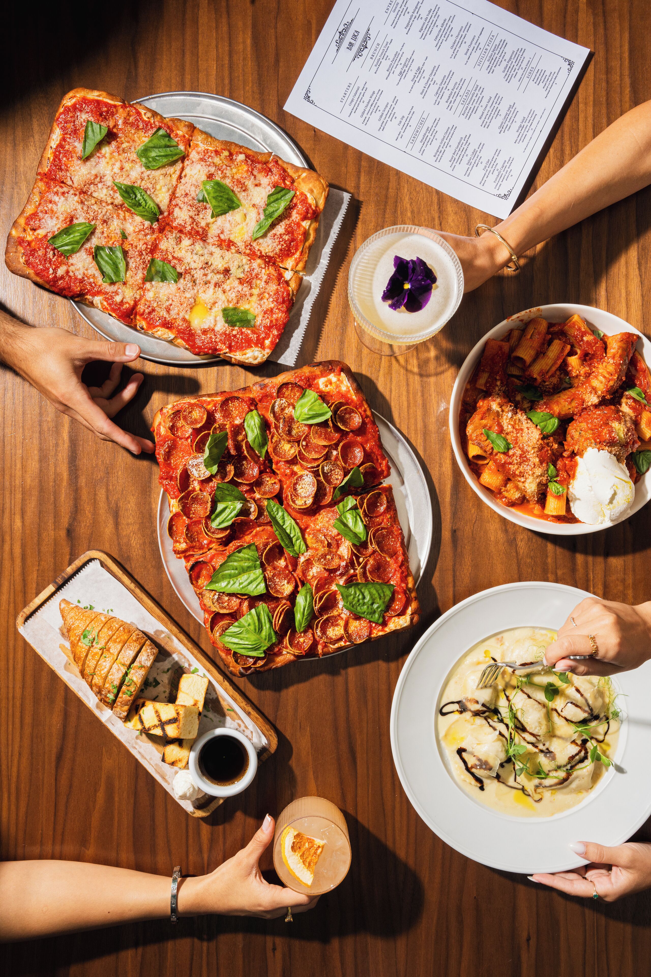 A dining table with various dishes, including pizza, pasta, and bread, along with a menu.