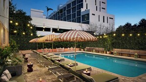 Un área junto a la piscina con sillones de descanso, sombrillas a rayas y velas.