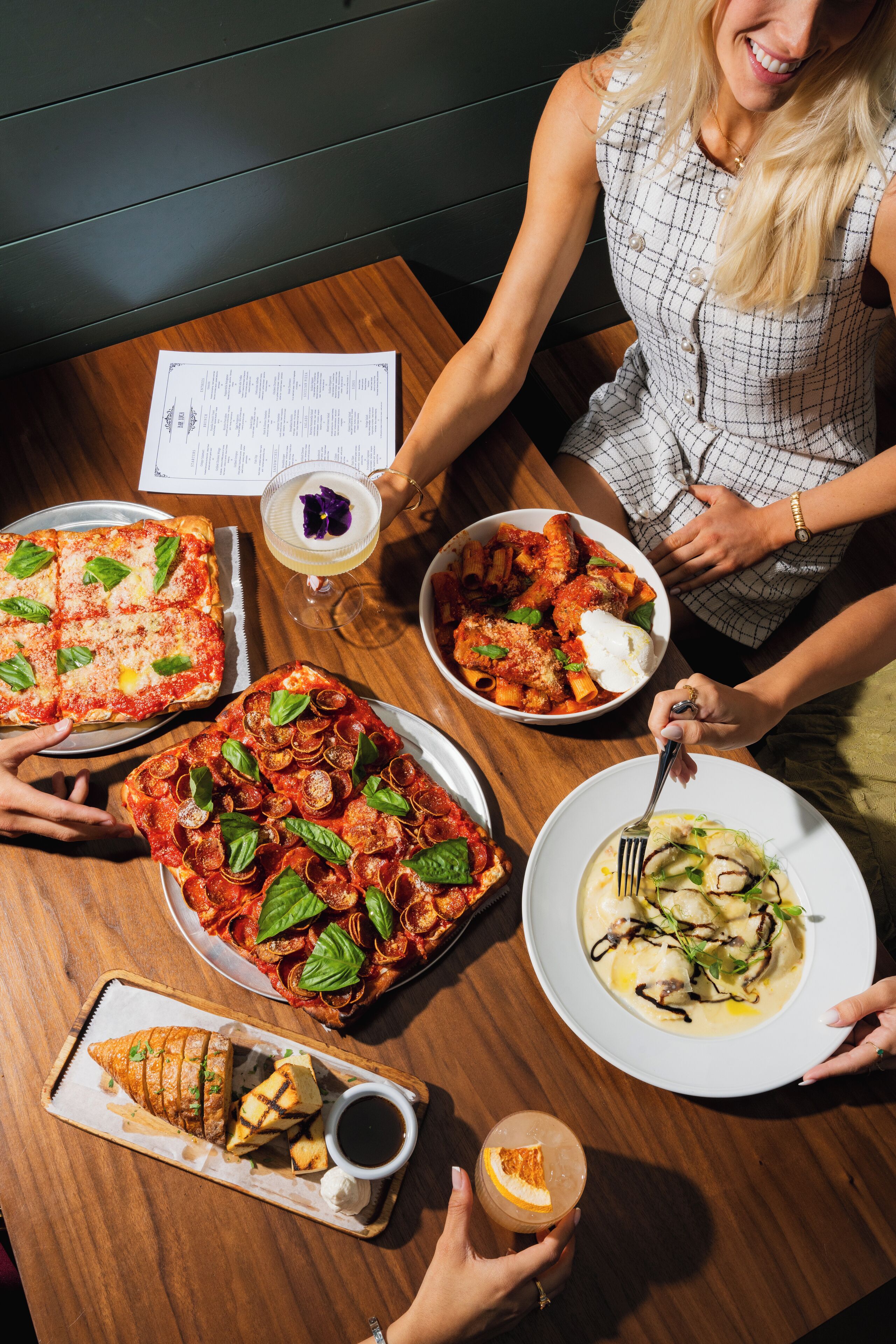 Una mesa de comedor con diversos platos, como pizza, pasta y un postre.