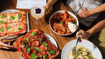 Una mesa de comedor con diversos platos, como pizza, pasta y un postre.