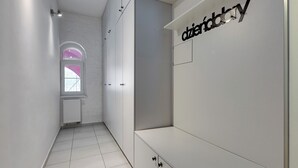 A hallway with white walls, a radiator, and a window with pink framing. - City Center Art House by Downtown Apartments (Gdansk)