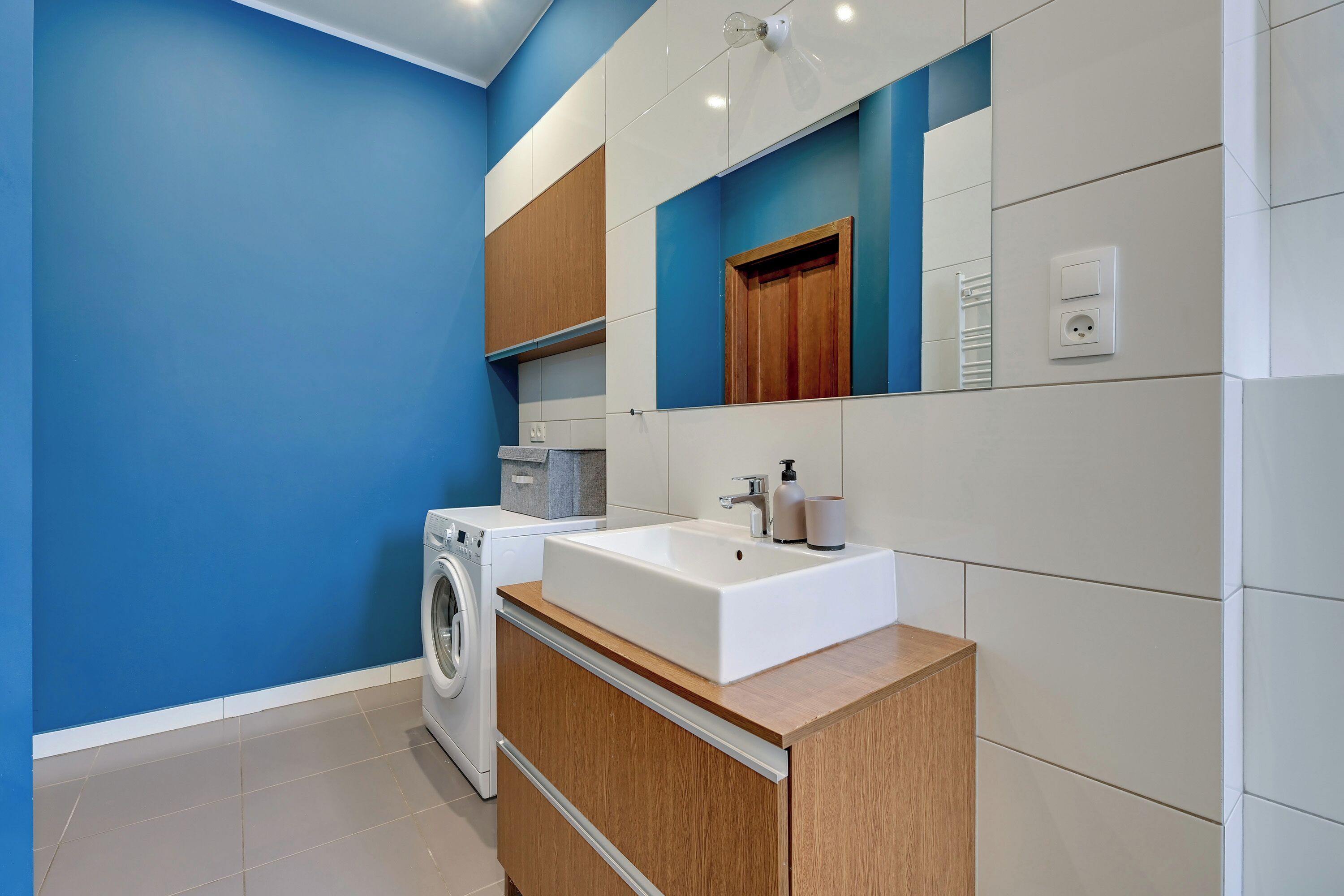 Un bagno moderno con un lavandino grande, una lavatrice e mobili in legno.
