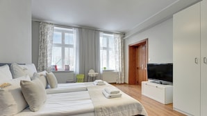 A modern bedroom with a large bed, a TV, and a wardrobe. - City Center Art House by Downtown Apartments (Gdansk)