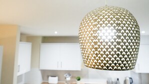 A kitchen with white cabinets and a hanging pendant light with a geometric pattern.