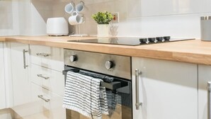 A modern kitchen with white cabinetry, a stainless steel range hood, and a built-in oven.