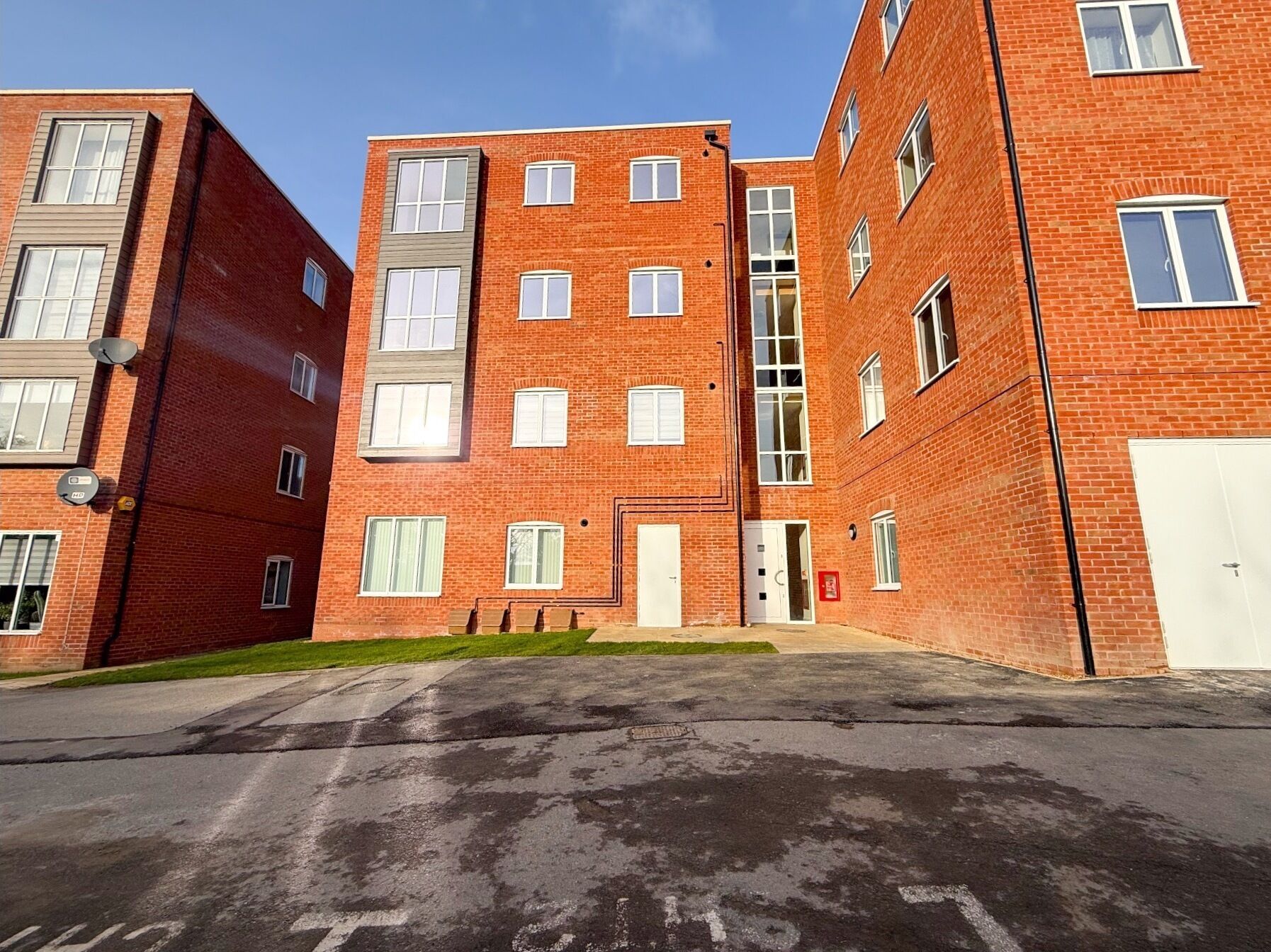 A multi-story brick building with a central entrance and multiple windows.