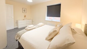 A bedroom with a bed, a dresser, a window with a blind, and a radiator.