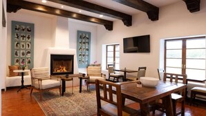 A cozy living room with a fireplace, wooden furniture, and artwork on the walls.