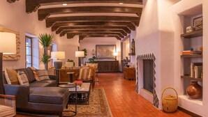 A spacious living room with a fireplace, a dining area, and a kitchen in the background.