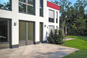 A modern building with large glass doors, a red roof, and a well-maintained lawn.