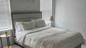 A neatly arranged bedroom with a large bed, two bedside tables, and a hanging light fixture.
