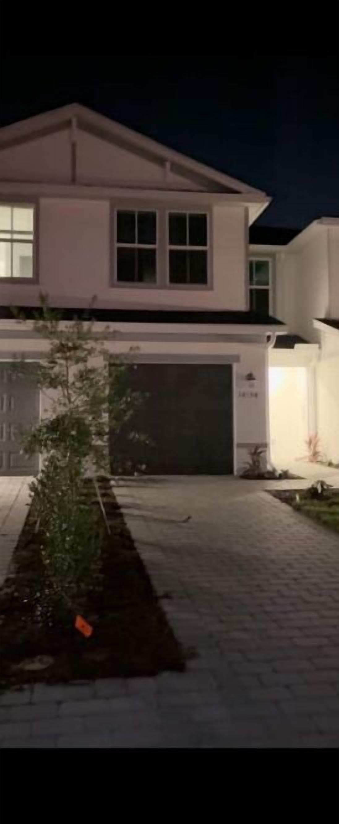 A modern two-story house with a garage, a well-maintained lawn, and a paved driveway.