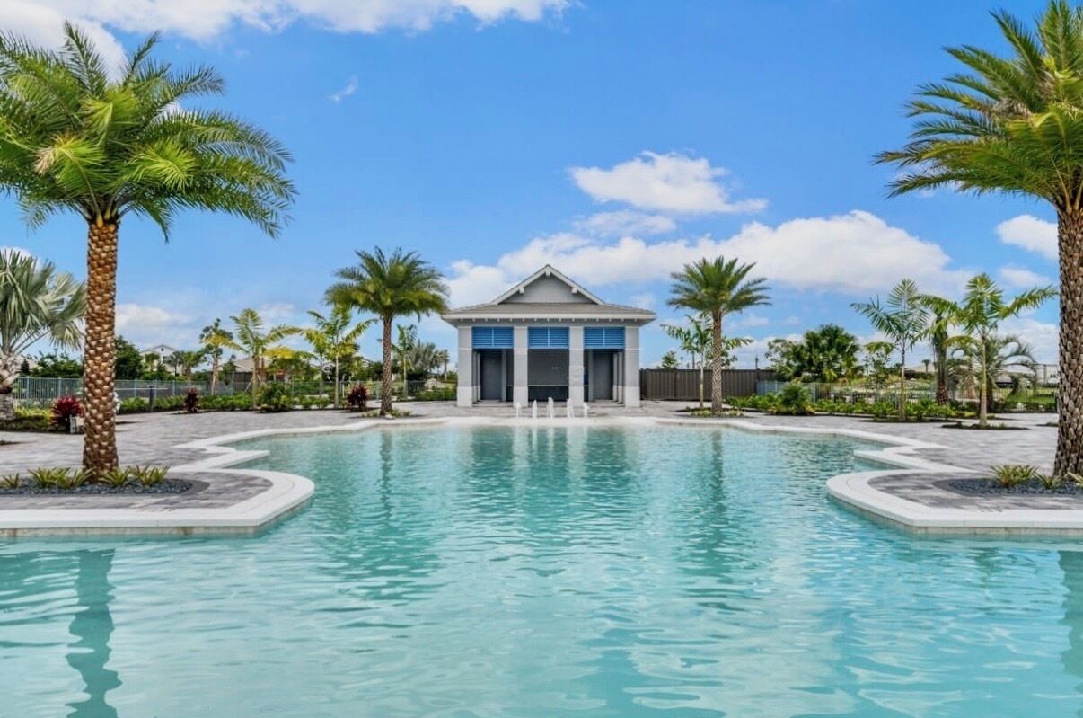 A swimming pool with a building in the background, surrounded by palm trees.