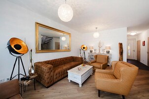 A living room with a large mirror, a brown sofa, a white coffee table, and a floor lamp.