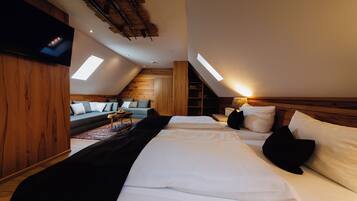 A bedroom with a large bed, a sofa, and a TV mounted on the wall.
