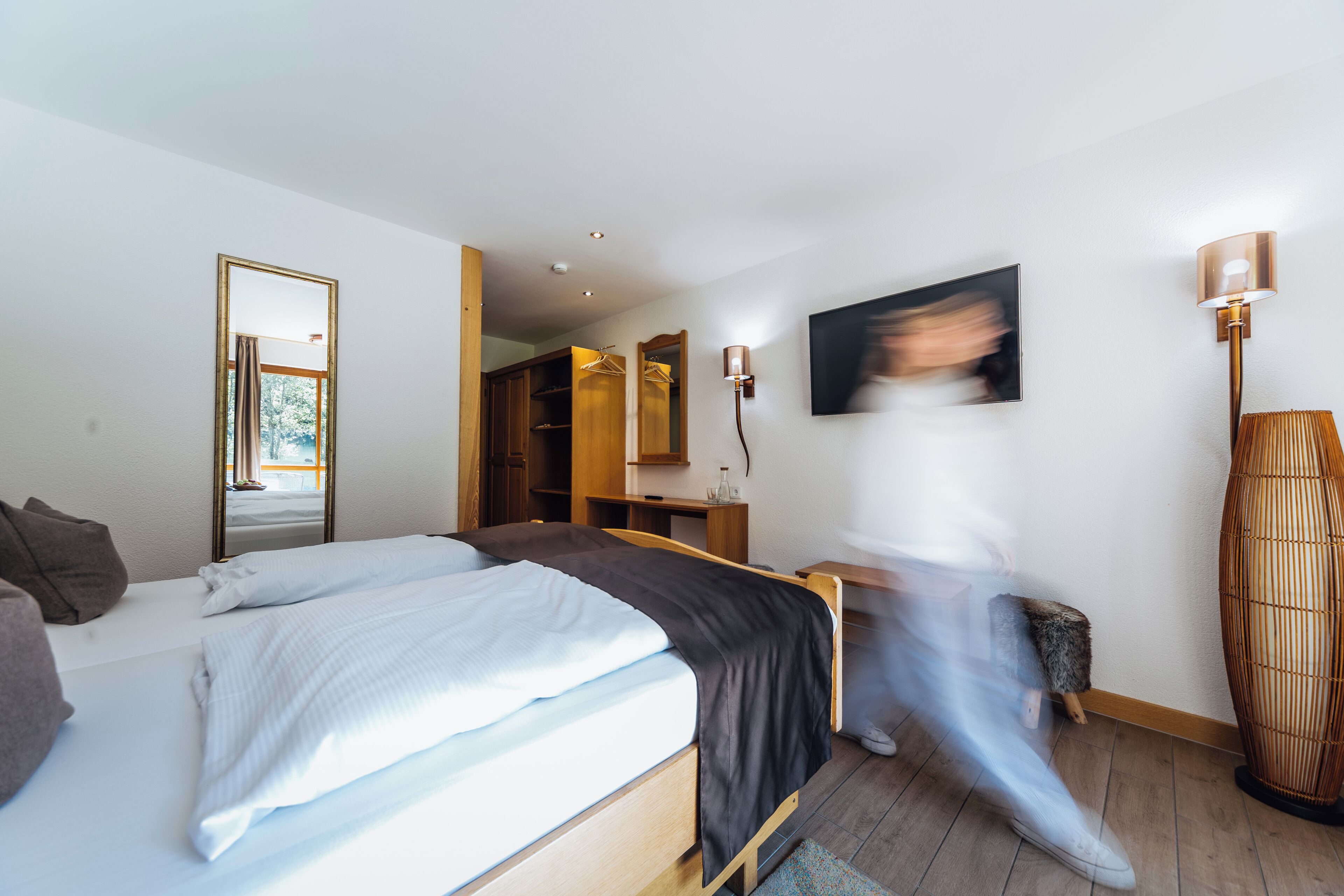 Une chambre d’hôtel moderne équipée d’un grand lit, d’une armoire, d’un bureau et d’un miroir.
